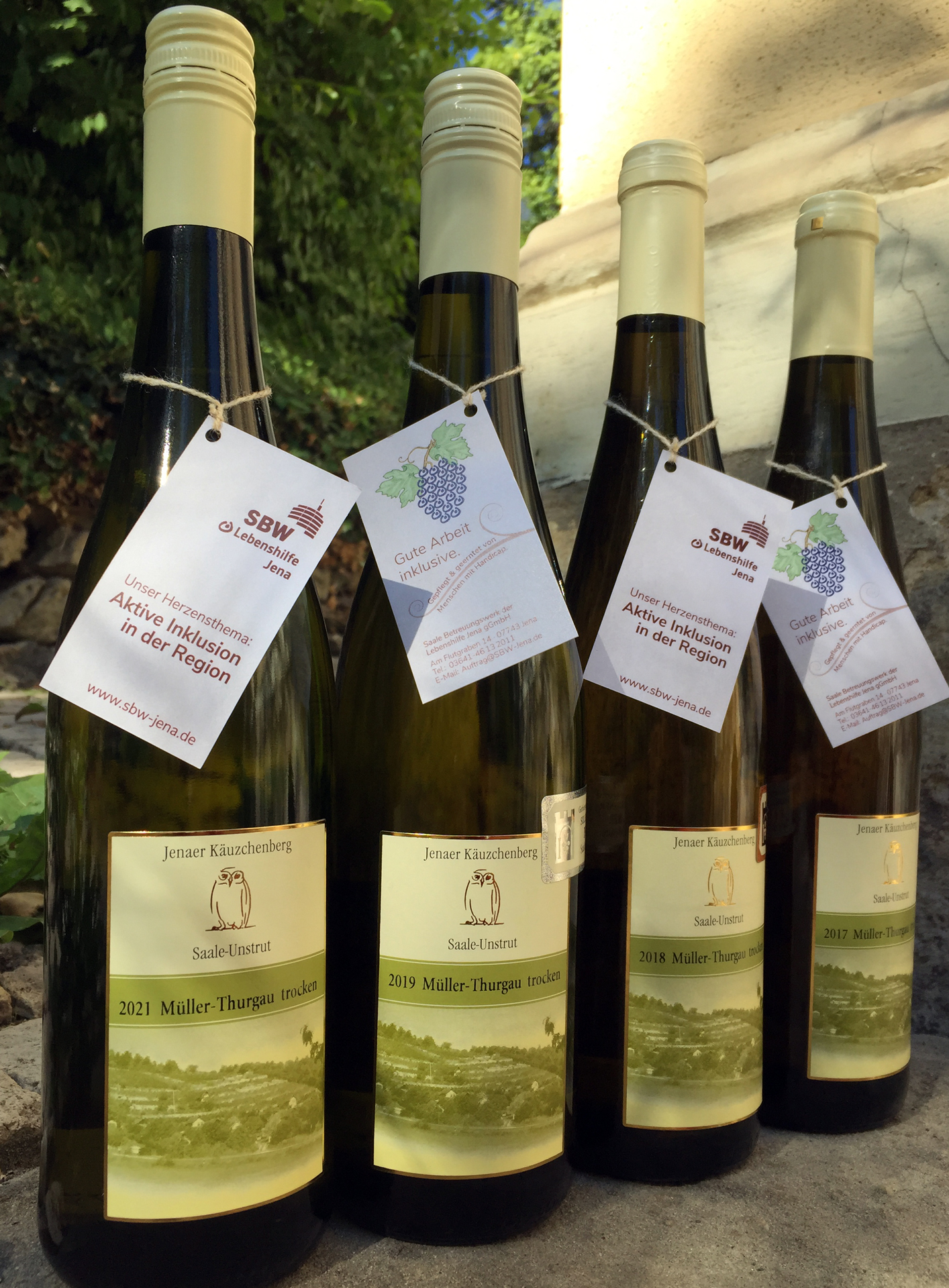 Auf dem Bild sind vier Jahrgänge des Weißweins Müller-Thurgau mit dem Etikett vom Jenaer Käuzchenberg in Flaschen zu sehen.