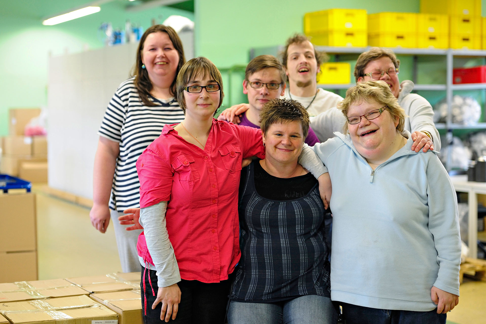 Im Bild zu sehen sind Teilnehmer aus dem Projekt „Jena inklusiv”. Sie halten sich in den Armen und lachen.