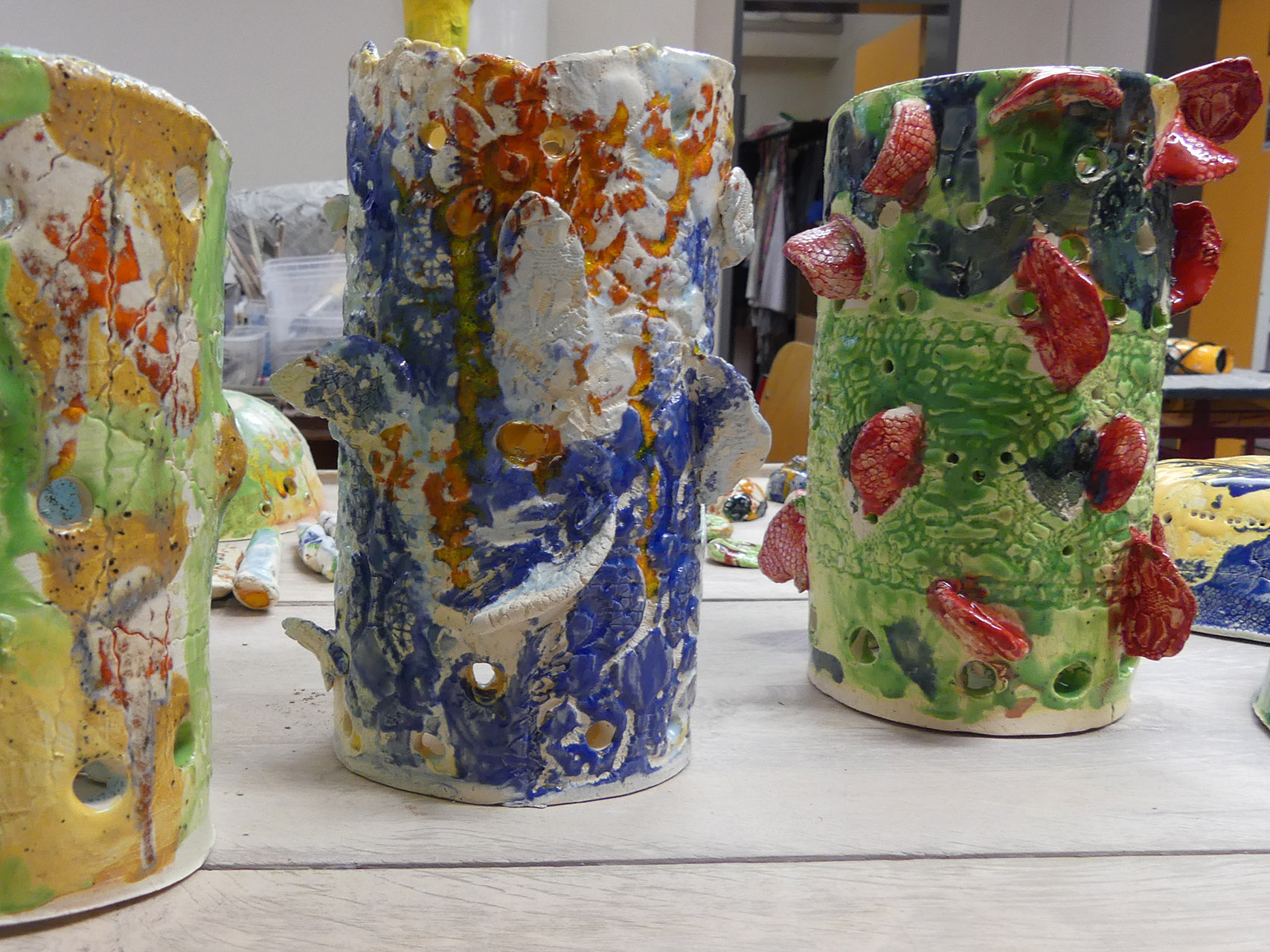Im Bild sieht man drei vasen-ähnliche Gefäße. Sie sind sehr bunt und fantasie-voll gestaltet.